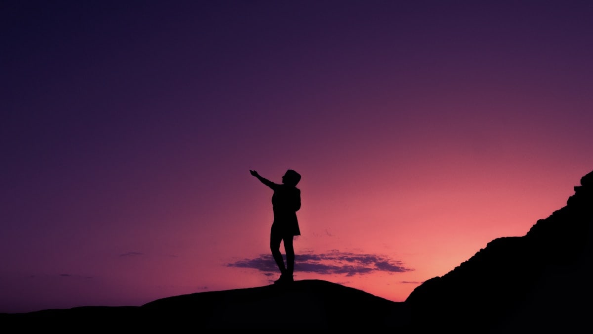 silhouette of man standing on rock during sunset